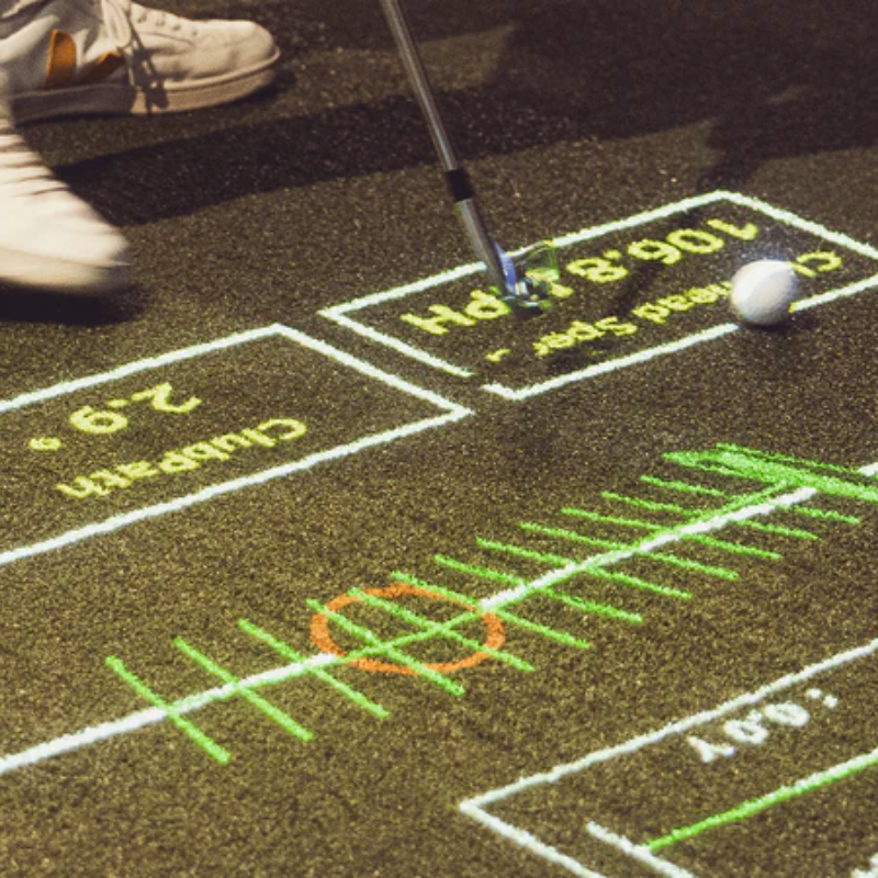 Foresight Sports Focus Club Tracer System person using club over projected data on green surface.