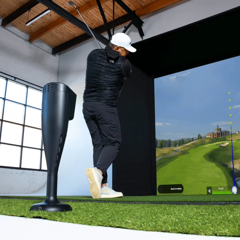 Red Stakes Golf One Golf Launch Monitor low view of man swinging in an indoor simulator.