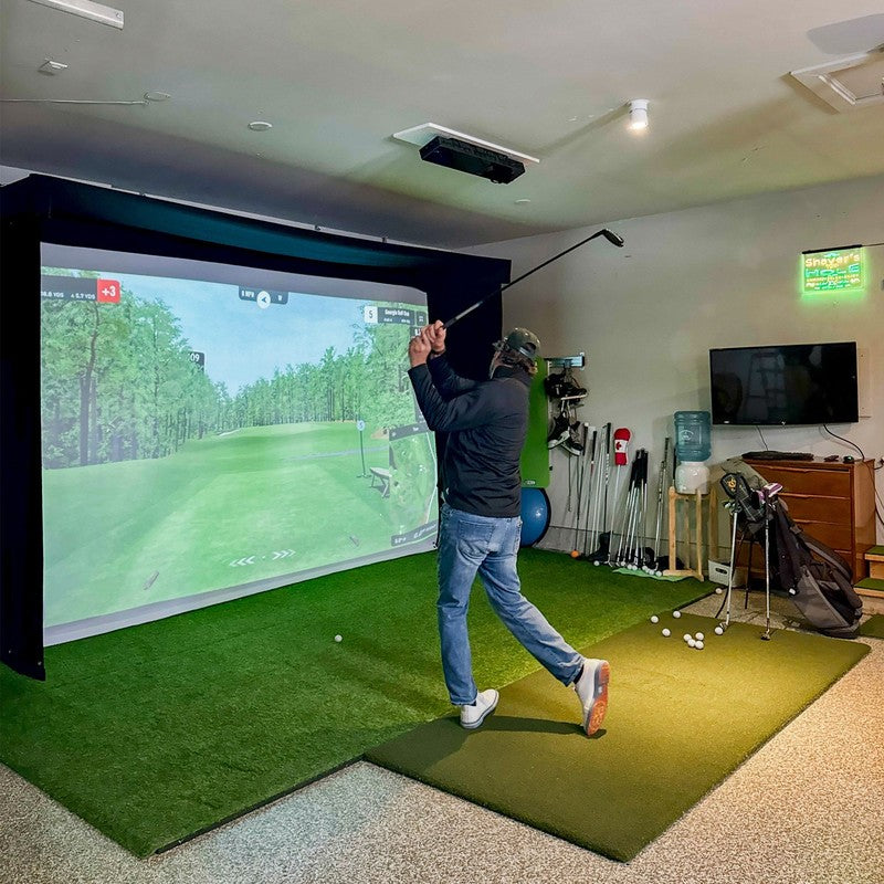 The SportsScreen Vanish LITE Series Golf Simulator Enclosure golfer swinging in a home simulator room.