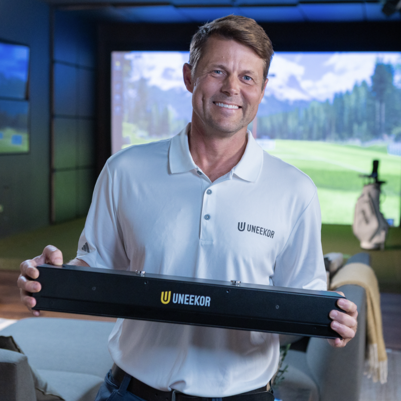 Uneekor EYE XR Launch Monitor being displayed by a man.